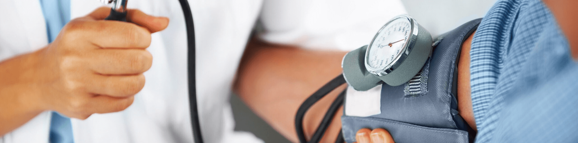 A healthcare professional measuring a patient's blood pressure using a sphygmomanometer and stethoscope.