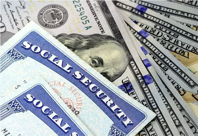 Close-up of Social Security cards overlapping US dollar bills, including $20 and $10 notes, with part of a US passport visible in the background.